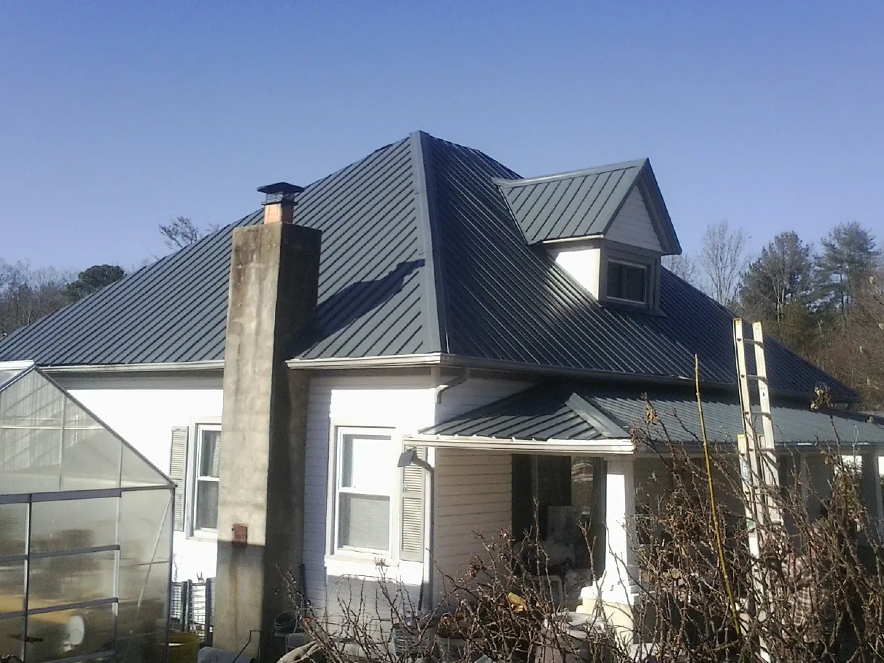 Dark blue standing seam metal roof on a white farmhouse with dormer — Slate & Tile Roof Repair by Roofing Brothers in Laporte