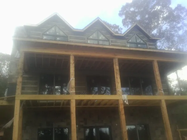 Dormers and porch framing on a large log home under construction — Roof Coating work by our crew in Laporte